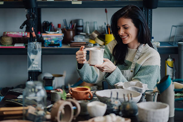 istock Female ceramic artist examining handcrafted mug in workshop 2208552928