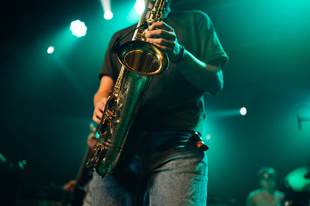 Saxophonist playing saxophone during a live concert under teal stage lights
