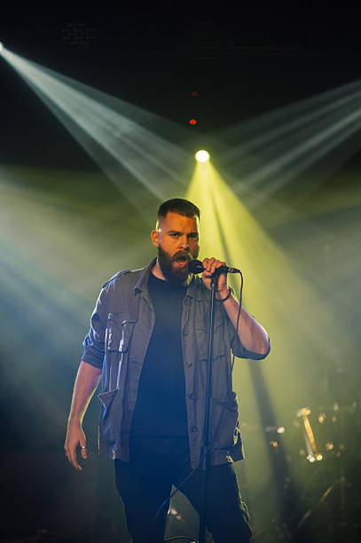istock Singer performing on stage with microphone and stage lights 2208556753