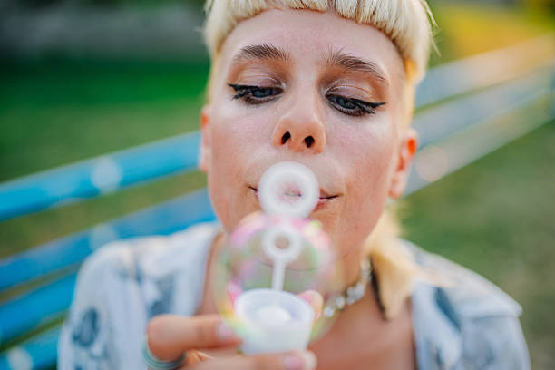 Blonde woman in sunglasses having fun and blowing soap bubbles on beach. Travel and beach lifestyle concept.