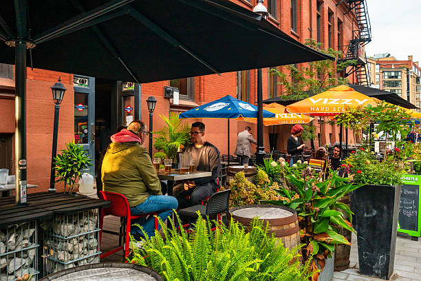 People sit on a restaurant bar patio in downtown Toronto Ontario Canada on a cloudy day.