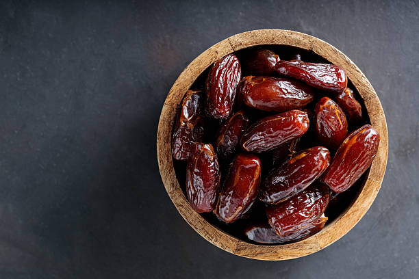 istock Dried Dates in Wooden Bowl on Dark Background, Top View, Copy Space 2208559660