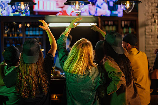 istock Excited friends cheering while watching sports in pub 2208559763