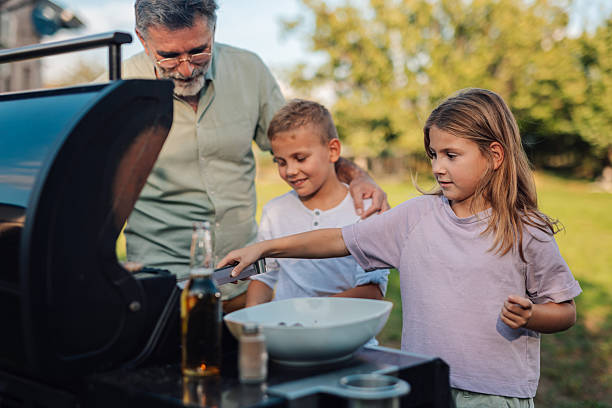 istock Grandfather grilling with grandchildren in backyard 2208573865