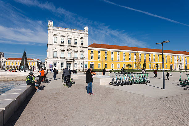 December 24, 2022, Lisbon Portugal. A vibrant city square featuring historic buildings, a clear blue sky, modern scooters, and people enjoying the atmosphere. Captured on a bright day in December, showing a blend of tradition and modernity.