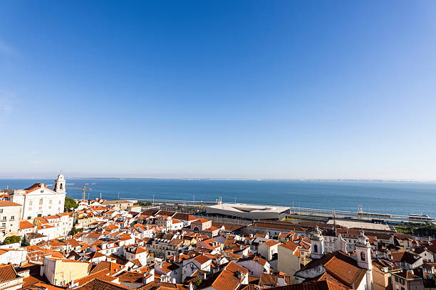 December 24, 2022, Lisbon Portugal. Vibrant rooftops of historic Lisbon on a bright, sunny day. Captures the essence of European coastal charm with serene ocean backdrop, inviting exploration and cultural experiences.