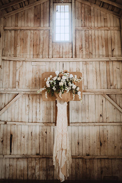 Lace wedding dress hanging inside of rustic barn Lace bride's wedding dress hanging inside rustic barn hoops wedding stock pictures, royalty-free photos & images