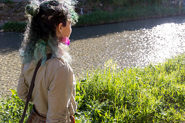 Young, mixed race, generation z woman walks along riverbank in springtime, Liguria