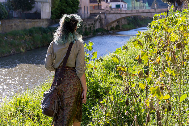 Young, mixed race, generation z woman walks along riverbank in springtime, Liguria