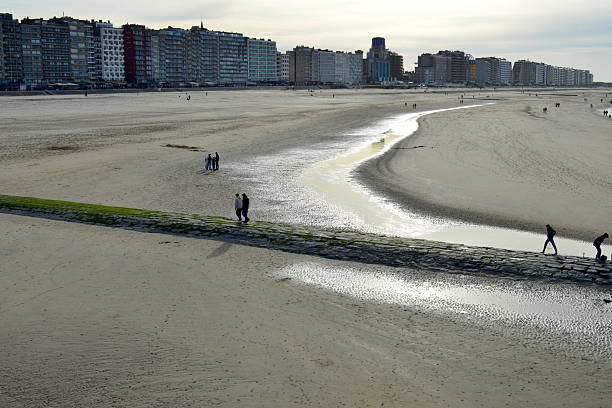 Blankenberge, West-Flanders, Belgium - February 23 2025: people silhouettes seen from the pier on the waterfront beach of Blankenberge on a sunny day in winter