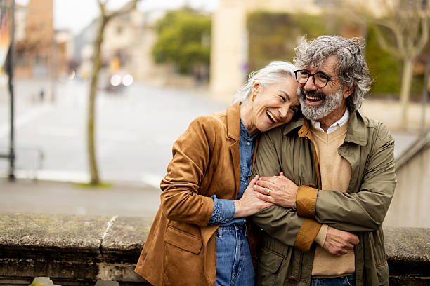 cheerful mature pair embracing their romantic escape in the urban setting - 65 69 jaar fotos stockfoto's en -beelden