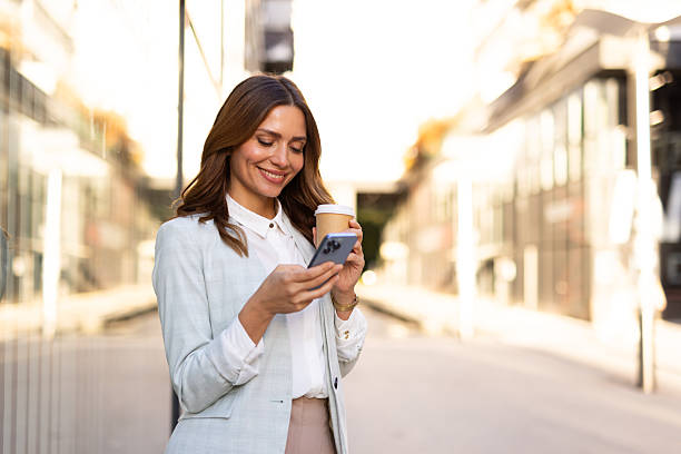 istock Businesswoman using smartphone and drinking coffee outdoors 2208614508