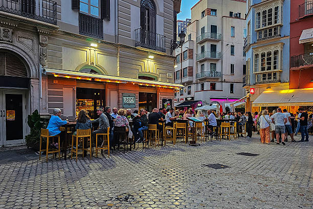 A waiter takes a customer's order in an outdoor plaza on a summer afternoon.
