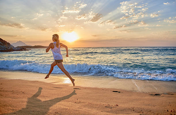 istock Beautiful woman running on the beach at sunset 2208617113