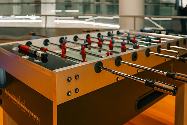istock Modern foosball table with red and blue player figures in a brightly lit indoor setting, featuring sleek metal rods and wooden handles 2208617178