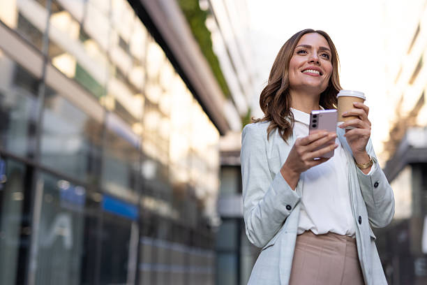 istock Businesswoman using smartphone and drinking coffee outdoors 2208619163