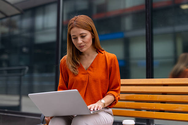 istock Businesswoman working on laptop outdoors on a bench 2208624240