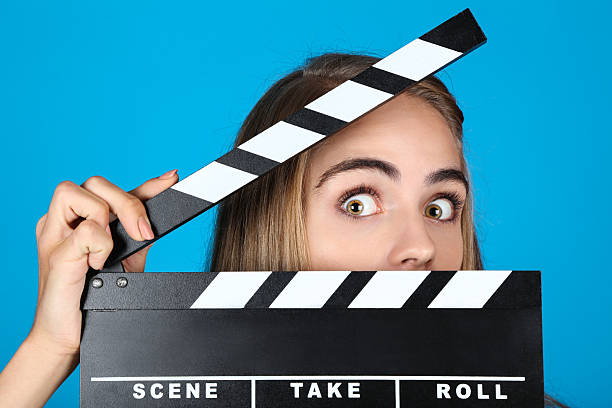 istock Beautiful girl with clapperboard on blue background 2208624475