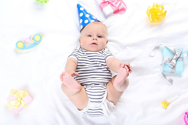 istock Baby boy with toys and gift boxes lying on white bed 2208627201