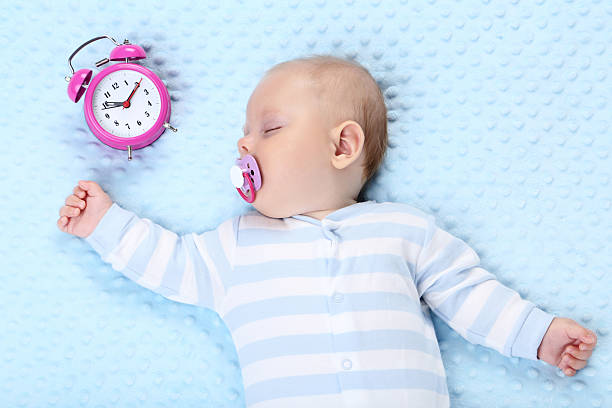 istock Baby boy with alarm clock sleeping in blue bed 2208627595