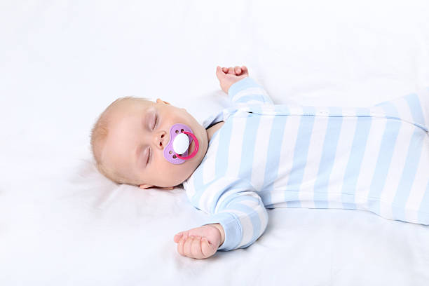istock Baby boy with soother sleeping in white bed 2208628388
