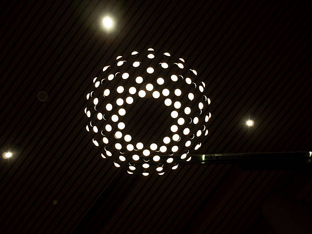 A light fixture is mounted on a wooden wall. The light fixture is white and has a silver base