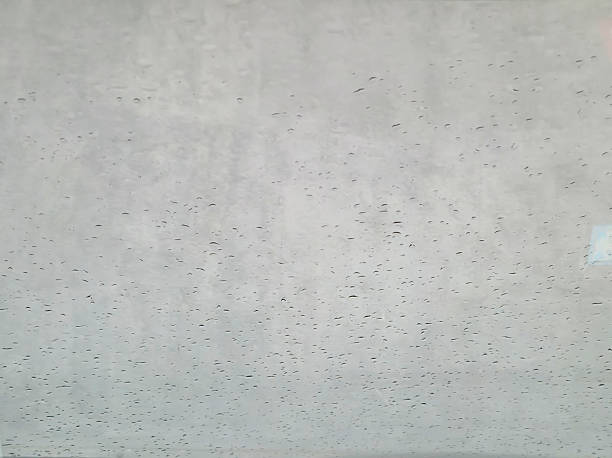 A close-up view of raindrops on a glass surface, creating a soothing, abstract texture. Ideal for backgrounds or themes of weather, tranquility, and clarity.
