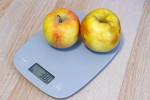 istock Two ripe apples on a modern kitchen scale, showcasing healthy eating and nutrition. Fresh fruits symbolize vitality and wellness in food preparation. 2208634139