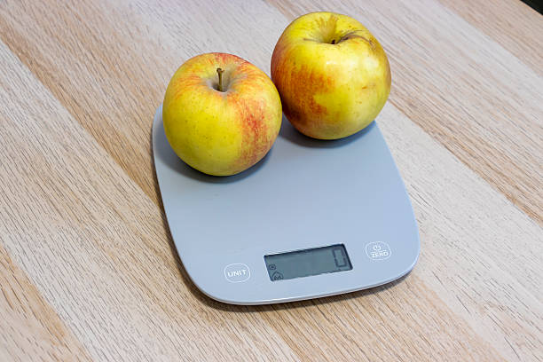istock Two yellow apples on a digital kitchen scale, ready for weighing. The image conveys freshness and healthy eating. Perfect for culinary or health-related content. 2208634214