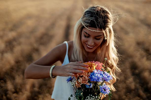 Portrait of a  beautiful blonde woman stands in a field, holding a vibrant flower bouquet and embracing the peacefulness of nature.