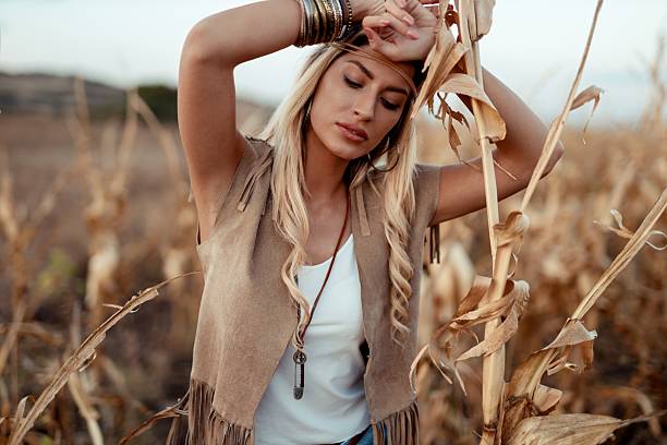 Capturing the soft, glowing light of the sunset, this image features a blonde woman standing in a vibrant field, radiating calm and contentment.