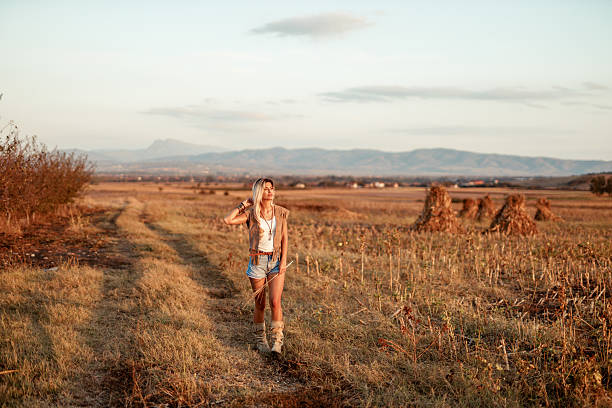 Beautiful blonde woman walking through a vibrant, sunlit field, embracing the simplicity and serenity of nature.