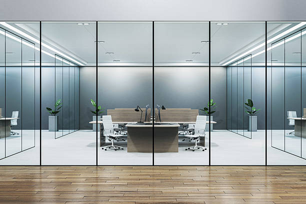 istock Modern glass-walled office interior with central workstations, white chairs, potted plants, and clean architectural design concept. 3D Rendering 2208636055