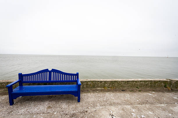 Lonely blue bench on a concrete pier under a cloudy sky in Nida Lithuania