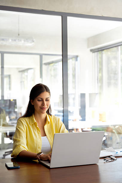 istock Young woman employee using computer for business work. Smiling latin girl learning student, professional pc user coder programmer working on laptop ai app sitting at desk in modern office. Vertical 2208637389