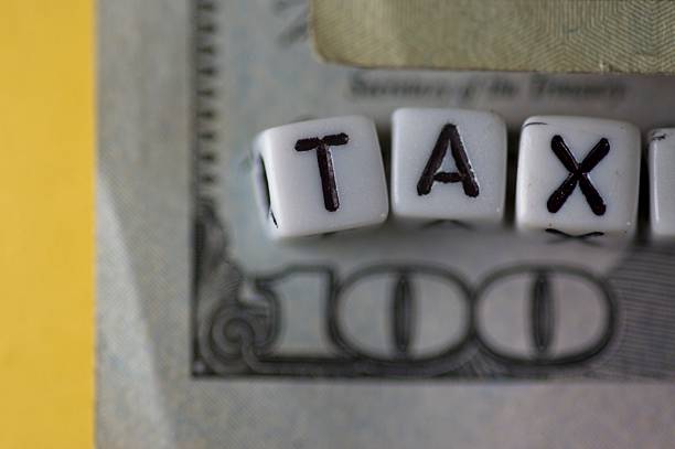 Lettered blocks spelling TAX on a 100 dollar bill