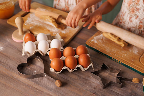istock Kids baking cookies, rolling dough with eggs and cutters on a kitchen table. 2208653982