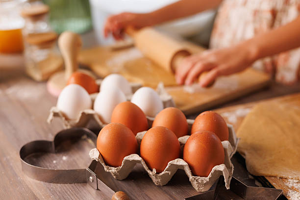 istock Eggs in foreground with hands rolling dough in cozy home kitchen. 2208653984