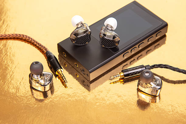 istock Wired earbuds with a stylish braided cable on a black audio player, reflecting on a gold surface. Perfect for tech product shots and music themes. 2208655371