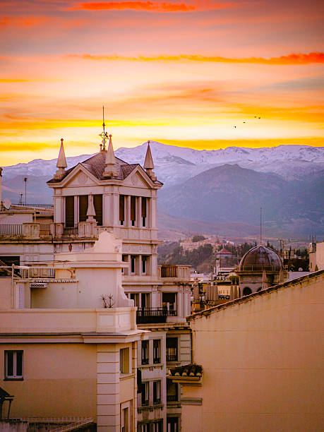 Breathtaking sunrise over Centro of Granada, Spain, with historic architecture and snow-capped Sierra Nevada mountains in the background. Perfect for travel and landscape enthusiasts.