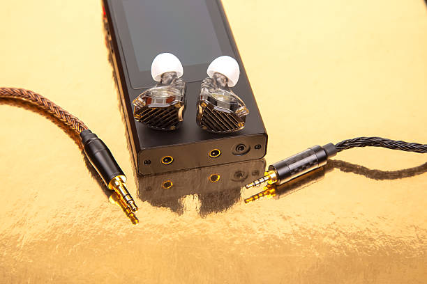 istock Elegant wired earbuds with a braided cable, placed on a black audio device against a shiny golden surface. Suitable for music, tech, and lifestyle photography 2208656636