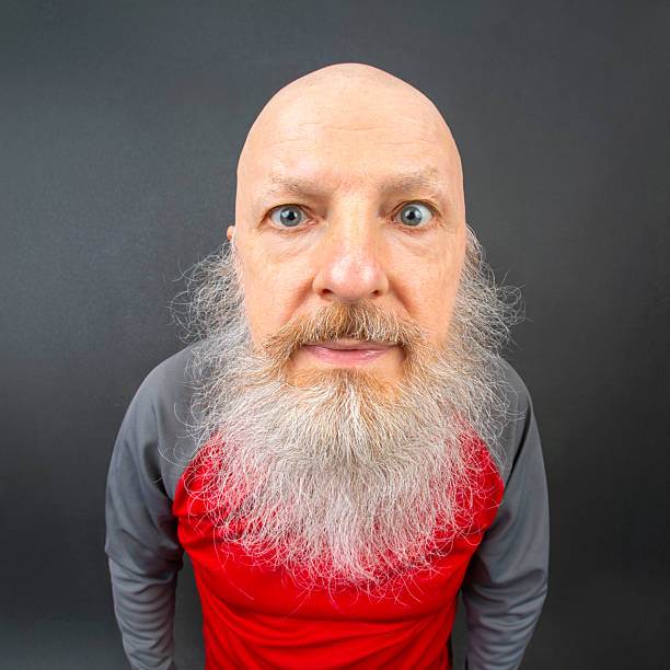 istock Elderly man with a long, white beard smiling widely against a dark background. His bright eyes and bald head emphasize his cheerful and friendly demeanor 2208656959