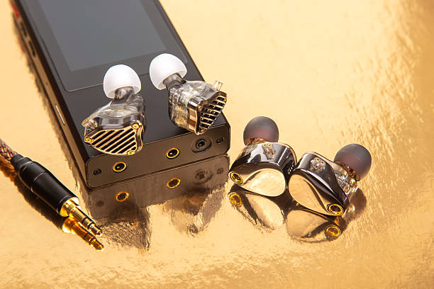 Wired earbuds on a black audio player with a gold backdrop, showcasing a braided cable. Great for technology, sound equipment, and design themes. High-quality image.