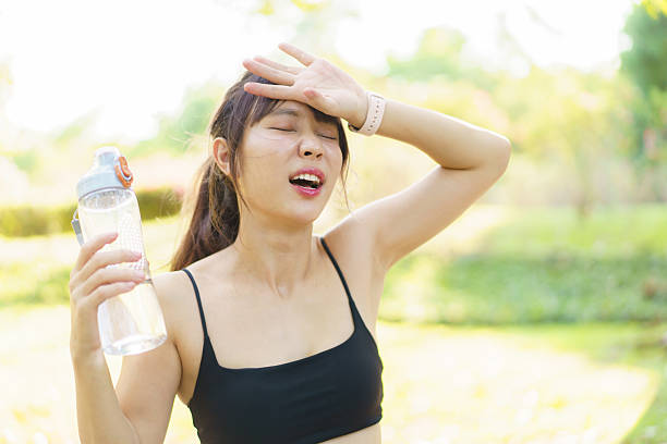 istock Asian woman take a break and drinks water from bottle after finished running. 2208667131