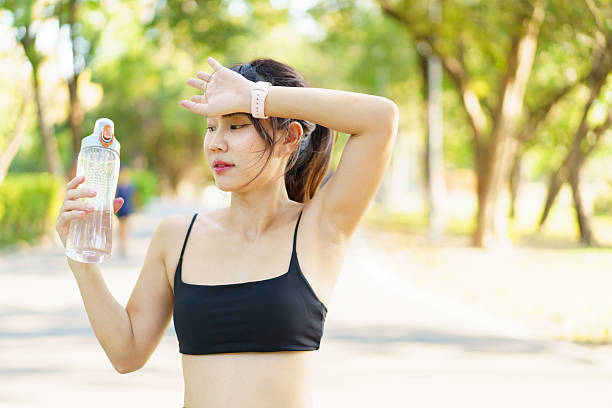 istock Asian woman take a break and drinks water from bottle after finished running. 2208667139