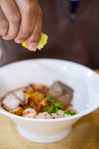 istock Male hand squeezing lime into a bowl of noodles 2208669820