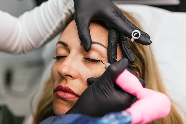 istock Beautician applying permanent eyeliner makeup tattoo on woman's eyelid 2208669938