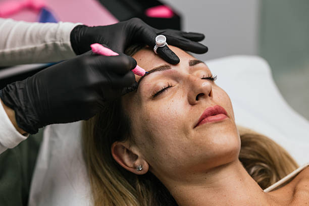 istock Beautician applying permanent makeup on eyebrows of client 2208670042