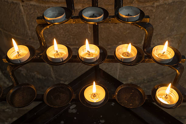 Lit tea lights seen on a wrought iron cable holder within an English cathedral. Used by visitors for prayer.