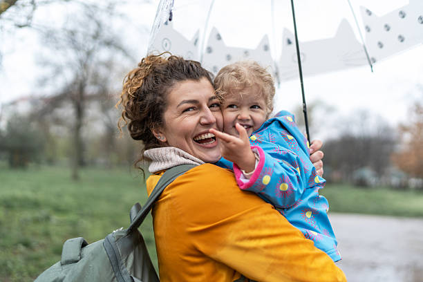 istock Excited mom and child under umbrella enjoying rain 2208679562